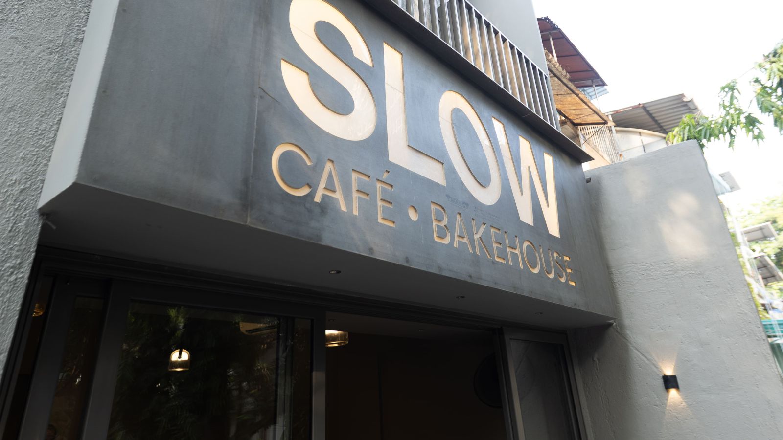 The illuminated SLOW Café and Bakehouse sign at the Kandivali entrance